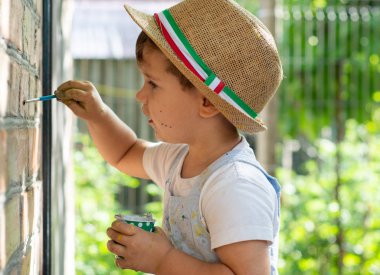 İki yıl eski çocuk duvara çiziyor. Boya fırçası ve suluboya ile küçük çocuk.