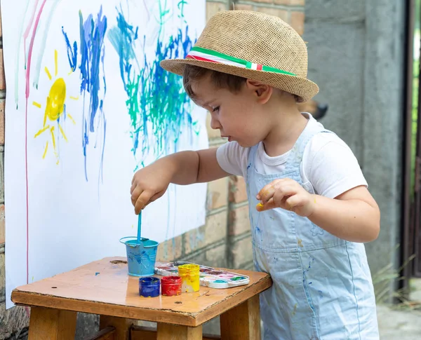 孩子拿着画笔在手和有乐趣的绘画与油漆 儿童发展概念 — 图库照片