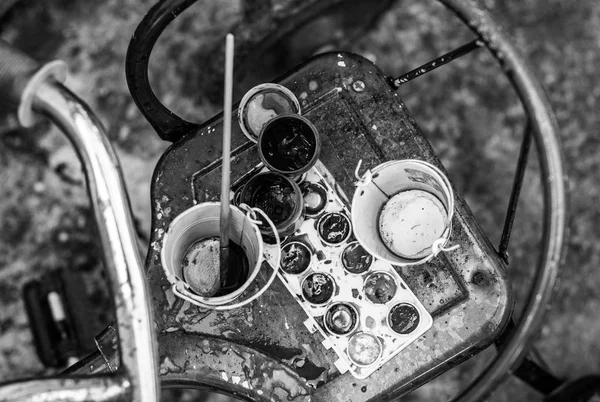 Opened paint buckets with brush. Art palette with brushes for painting and paints on the retro bicycle. Black and white.