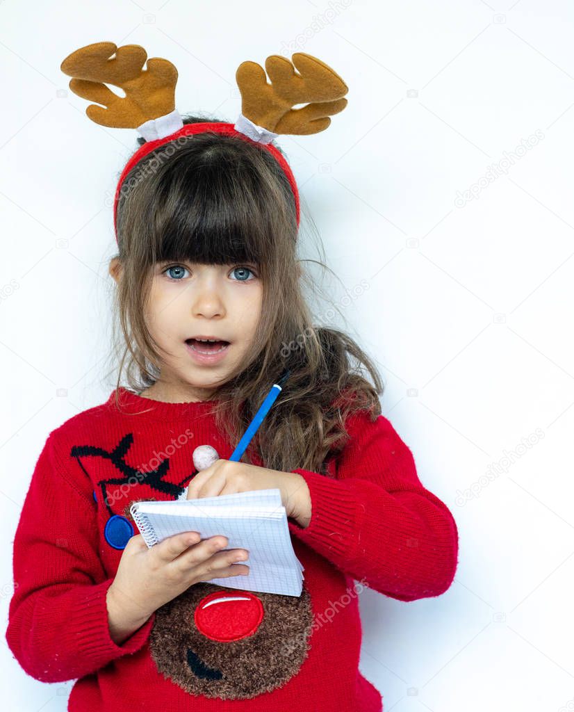 Christmas sale. Beautiful shocked kid holding pen and writing a shopping list. Emotions. Funny Laughing child Portrait. New year sales.