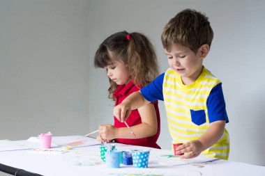 Sanat stüdyosu oynayan iki çocuklar. Dört yıl eski çocuk evde boyuyor. Boya fırçası ve suluboya ile güzel bir çocuk.