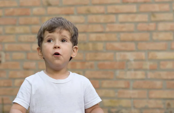 Niño Feliz Niño Camiseta Blanca Expresa Deleite Una Pared Ladrillo — Foto de Stock