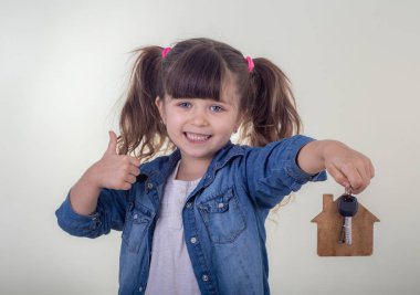 Mutlu kız gitmek için yeni bir ev taşımak için ve anahtarları için yeni bir daire tutar. Gri arka plan üzerinde izole.
