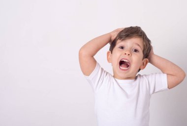Headshot etkilendim çekici küçük çocuk ağız açmak hayretle ve elele yüz ayakta yakınındaki beyaz duvardan şok. 