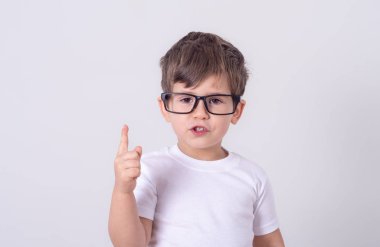 Dostu genç çocuk gülüyor ve gülümseyen sevinçle ellerini yükselterek ve gri arka plan üzerinde kopya alanı gösteren işaret kapalı atış 