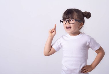 Dostça genç kız gülerek ve gülümseyen sevinçle ellerini yükselterek ve gri arka plan üzerinde kopya alanı gösteren işaret kapalı atış 