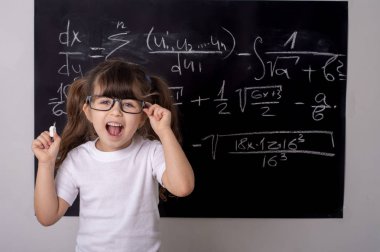 Çocuk eğitim. Öğrenci formu ile siyah yazı tahtası yakınındaki gözlüklü