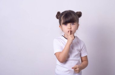 Shhh sign. Young girl showing shh gesture to keep a silent. Girl in template white t shirt keep a secret. Copy space  clipart
