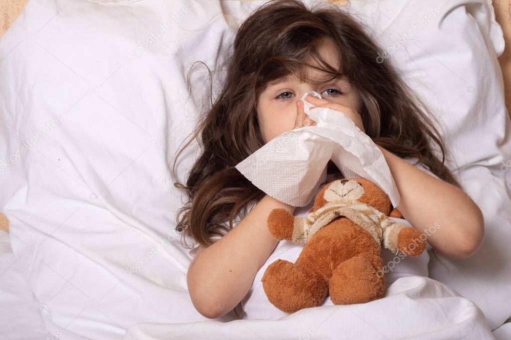 Sick kid blowing Nose. Napkins on bed. Kid treatment at Home. Disease and Illnesses. 