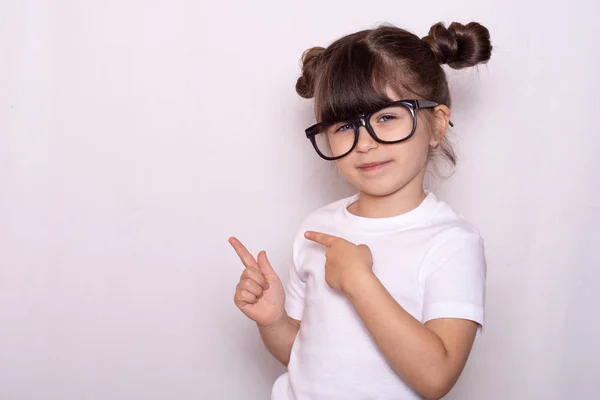 Child posing and smiling with expression, pointing finger free space for advertisement. Copy space