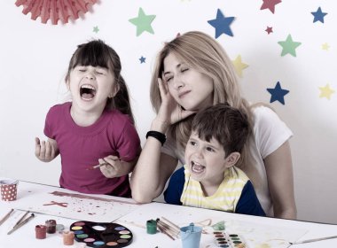 Yorgun anne. Evde oynayan iki çocuk, stresli bir anne zor itaatsiz çocuklar yetiştirmekten yorulmuş..