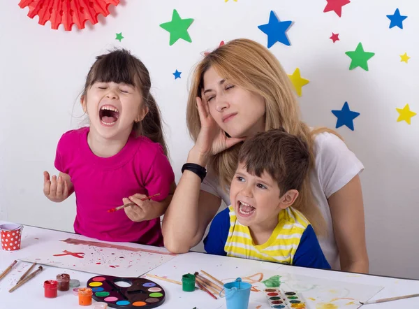 Yorgun anne. Evde oynayan iki çocuk, stresli bir anne zor itaatsiz çocuklar yetiştirmekten yorulmuş..