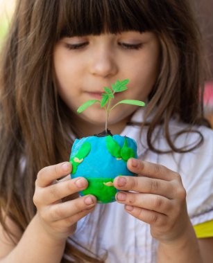Sevimli küçük kız dünyayı korumak. Dünya kavramını kurtarın. Yeşil bitki ile gezegene odaklanın. 