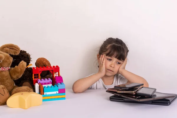 压力重重的小女孩坐在手机 智能手机 笔记本电脑 平板电脑附近 信息过载的概念 压力之下的孩子被信息淹没 — 图库照片