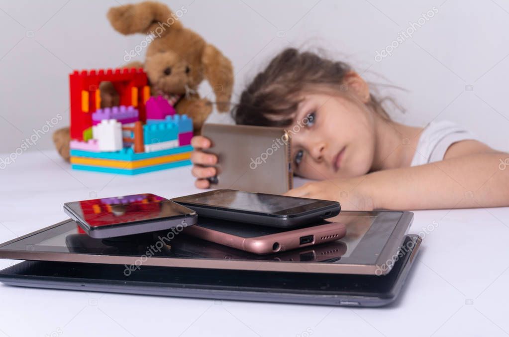 Little girl obsessed with phones mobile apps ignoring parents and toys at home, kid using smartphones checking social networks online, gadgets overuse concept.  Internet addiction