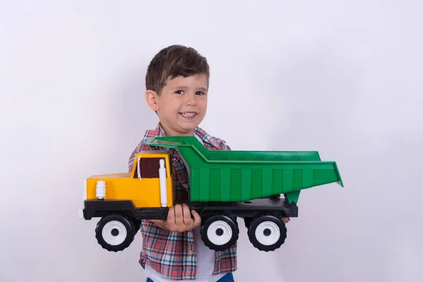 小さな幸せな少年は 白いスタジオの肖像画に隔離された彼の手でおもちゃの店からおもちゃの車を保持します — ストック写真