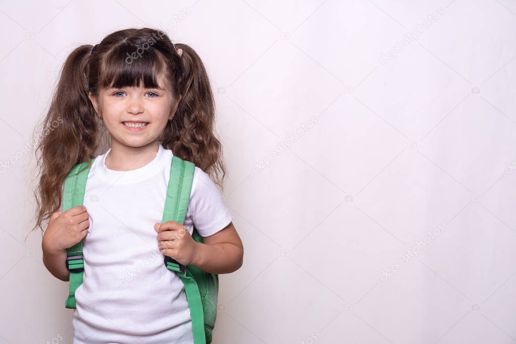 Back to school. Happy pupil with curly hair and blue eyes with schoolbag on white background. Free space for your text or advertisement. Child holding satchel. 
