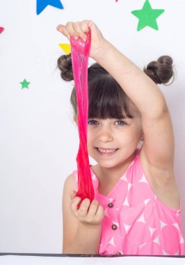 Cute funny girl play with slime. Kid squeeze and stretching toy slime. clipart