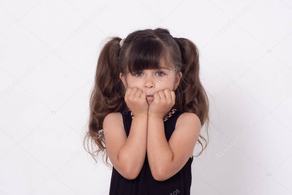 Kid shocked hearing something. Indoor shot of amazed and surprised happy curly hair kid girl, gasping, standing with hands near opened mouth and popping eyes, being stunned