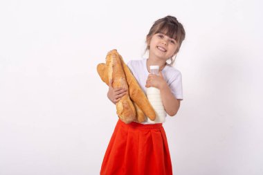 Elinde ekmek ve süt olan bir kız. Fırından elinde taze pişmiş ekmek. Çocuk elinde beyaz arka plan izole ekmek bir sürü tutuyor. 