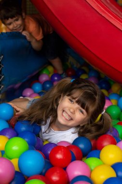 Top pit kapalı oyun alanı. Neşeli çocuk kapalı oyun merkezinde eğlenin. Çocuk oyun alanı top havuzunda renkli topları ile oynuyor. Tatil veya Doğum günü. 