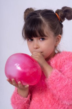 Pembe bir balçıktan büyük baloncuklar yapan çocuk. Kız sıkmak ve oyuncak balçık germe.