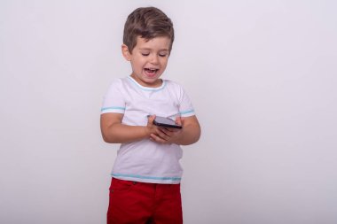 Sevimli mutlu yürümeye başlayan akıllı telefon tutan. Dört yaşında bir çocuk, gri renkte izole edilmiş, reklam metni için yer. Modern teknoloji. 