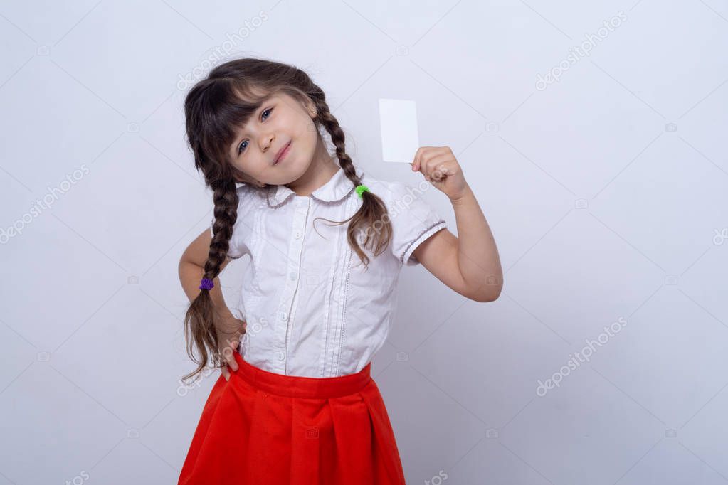 Child showing empty blank paper, copy space. Kid holding credit card in hands. Realistic white mockup of a bank or gift card. Ready to used in your showcase.
