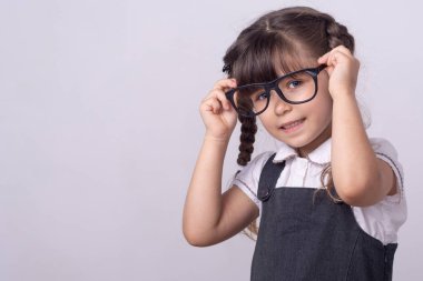 Akıllı küçük okul çocuğu gri arka plan üzerinde parlak bir fikir var. Dahice fikirleri olan küçük bir kız. Mutlu çocuk dehası veya wunderkind.