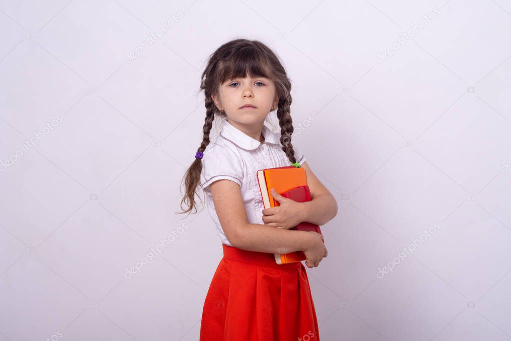 Smart school girl taking red and orange books in the hands. She is ready for back to school season. 