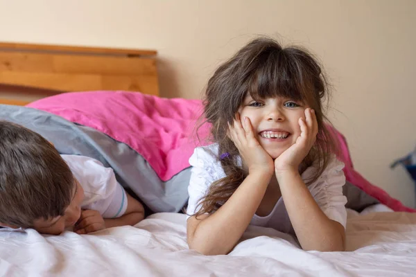 两个快乐的兄弟姐妹睡觉前在床上玩得很开心 孩子们躺在毯子下躺在床上 面带微笑 — 图库照片