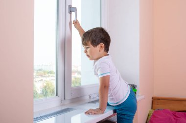 Pencereyi açmaya çalışan bir çocuk kolunu çekiyor. Evde Çocuk Güvenliği Penceresi Kısıtlayıcılar.  