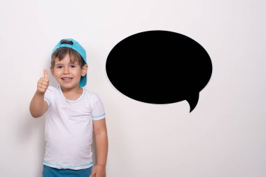 Gülümseyen küçük çocuk başparmağını kaldırıyor. Boş mesaj balonu. Reklam metni için kullanılabilir Kopyalama Alanı. 
