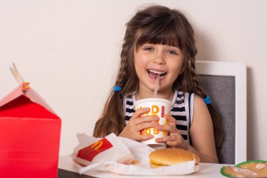 Ukrayna, Kyiv - 5 Ekim 2019: gülümseyen kız elinde McDonald 's restoranından aldığı mutlu yemek paketini tutuyor.