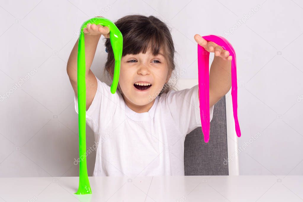 Child play with slime. Little girl squeeze and stretching pink and green slime.