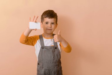 Çocuk kartını gösteriyor. İndirim kartı olan mutlu okul çocuğu. Çocuklar ve finans veya satış.