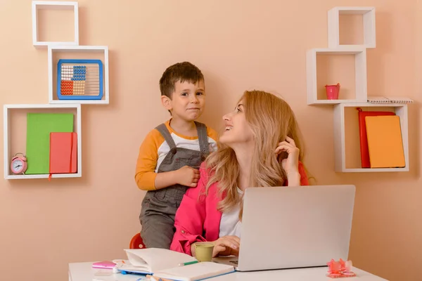 快乐的妈妈在家里工作 在家工作 妈妈在笔记本电脑上工作 孩子们在那里玩耍 — 图库照片
