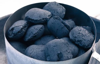 A pile of coal on a barbeque, getting ready for a summer grill.