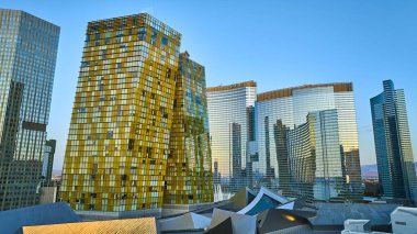 Las Vegas şehir merkezinin çarpıcı hava manzarası parıldayan gökdelenler altın saat yansımaları ve açık mavi gökyüzünün altındaki Strip siluetinin dinamik enerjisi.