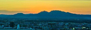 Las Vegas şehir merkezinin altın saatinde gökyüzü manzarası. Strip Skyline parlak şehir ışıkları ve çarpıcı bir panoramik manzara oluşturan uzak dağlar..