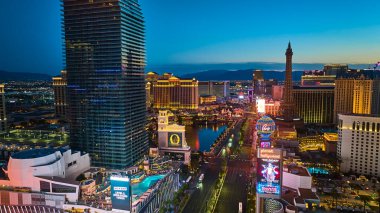 Las Vegas Bulvarı 'nın altın saatindeki hava manzarasında Kozmopolit Kulesi Paris Oteli kopyası ve Nevada' daki canlı şehir ışıkları yer alıyor..