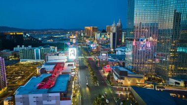 Nevada 'daki Las Vegas Bulvarı' nın altın saatindeki hava manzarasında neon ışıklar modern oteller ve derin mavi bir gökyüzünün altındaki canlı şehir silueti yer alıyor..