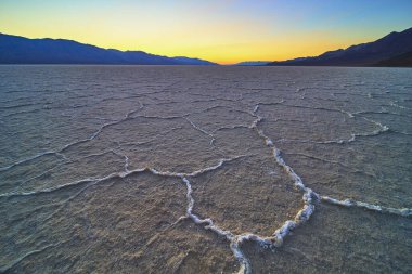 Nevada Ölüm Vadisi 'ndeki Badwater Havzası' nın tuzlu düzlükleri, uzak dağlar ve sakin bir gökyüzünün dramatik ve sakin bir manzara oluşturduğu altın saat içinde ayrıntılı örüntüler gösteriyor..