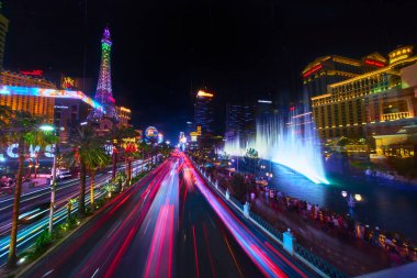 Las Vegas 'taki The Strip' in canlı, uzun gece sahnesinde trafik ışıklarının yol açtığı göz kamaştırıcı çeşmeler ve şehrin ünlü gece enerjisini yakalayan renkli neon tabelalar vardı..