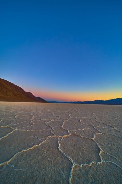Badwater Ölüm Havzası 'ndaki tuzlu daireler Nevada' da uçsuz bucaksız bir gökyüzü altında altın saat ışığıyla parıldıyor. Amerika Birleşik Devletleri 'nde çarpıcı bir toprak yalnızlığı ve doğal harikalar manzarası yaratıyor..