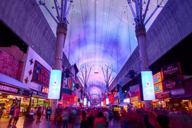 Canlı bir kalabalık Las Vegas Nevada 'daki aydınlık Fremont Street Experience keyfini çıkarıyor. Canlı LED tepe örtüsü neon ışıkları ve ikonik işaretler ile enerjik bir kentsel atmosfer yaratıyor..