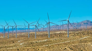 Mojave Çölü 'ndeki rüzgâr türbinlerinin havadan görünüşü Kaliforniya' nın berrak gökyüzü altında kurak tepeler ve uzak dağlar Amerika 'da yenilenebilir enerji ve sürdürülebilir gücü vurguluyor..