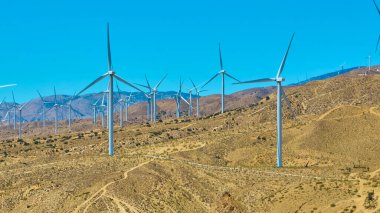 Kaliforniya 'daki kuru Mojave arazisinden yükselen rüzgar türbinleri, açık mavi gökyüzü altında etkileyici bir hava görüşü ile ABD' deki yenilenebilir enerji ölçeğini yakalıyor..
