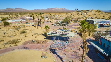 California 'daki terk edilmiş Dolores Gölü su parkının hava manzarası. Canlı grafiti palmiyeleri ve berrak mavi gökyüzünün altında geniş bir çöl manzarası var..