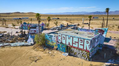 Kaliforniya çölündeki Dolores Gölü 'ndeki terk edilmiş binaların ve palmiye ağaçlarının parlak güneş ışığı ve şehir keşfi konsepti için uzak dağlara bakan hava manzarası..